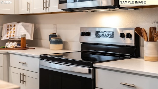 kitchen with stainless steel electric stove, light countertops, and white cabinetry