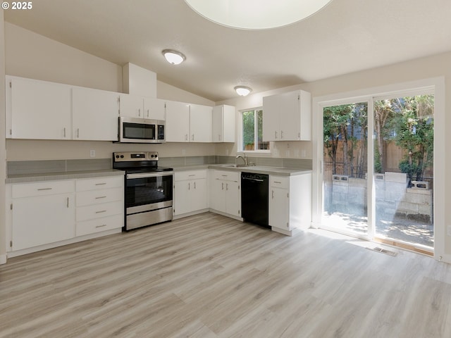 4549 SE Knapp St, Portland, OR 97206 - kitchen with stainless steel appliances, vaulted ceiling, white cabinets, light wood-style floors, and light countertops