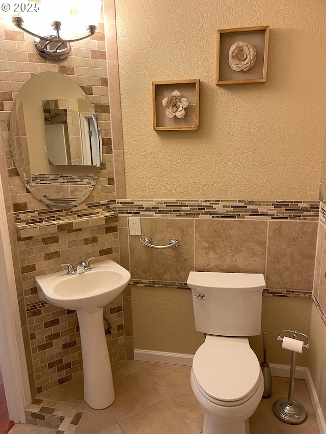 half bath with tile patterned flooring, tile walls, and toilet