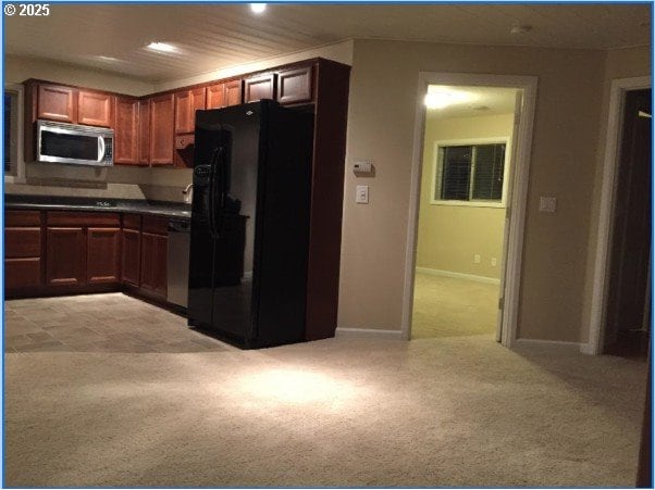 kitchen with stainless steel appliances, baseboards, light colored carpet, and dark countertops