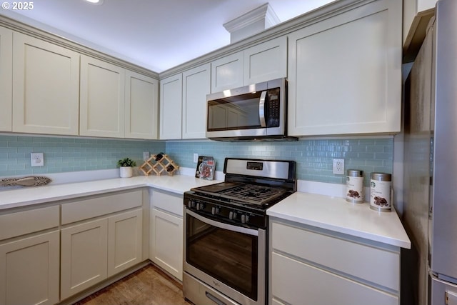 27 NW 6th Pl, Warrenton, OR 97146 - kitchen featuring light wood-style flooring, appliances with stainless steel finishes, tasteful backsplash, and light countertops