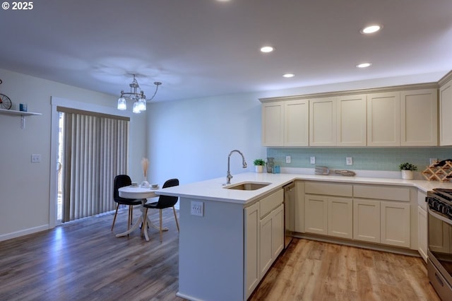 27 NW 6th Pl, Warrenton, OR 97146 - kitchen with a peninsula, light wood-style flooring, a sink, and stainless steel appliances