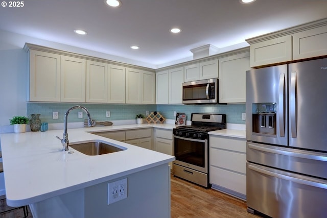 27 NW 6th Pl, Warrenton, OR 97146 - kitchen with a peninsula, a sink, decorative backsplash, light countertops, and appliances with stainless steel finishes