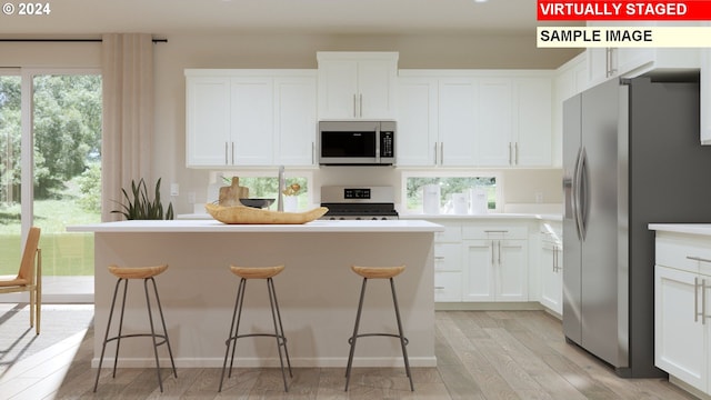 kitchen featuring a breakfast bar, appliances with stainless steel finishes, and white cabinetry