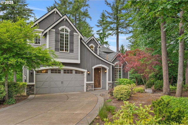 view of front of house with stone siding, an attached garage, and driveway