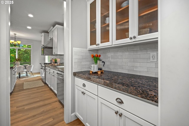 kitchen with appliances with stainless steel finishes, dark wood finished floors, backsplash, white cabinetry, and glass insert cabinets