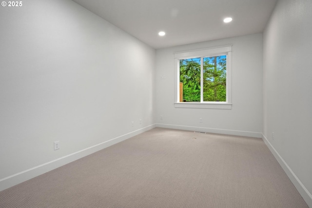empty room featuring light carpet, baseboards, and recessed lighting