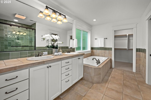 bathroom featuring a shower stall, tile patterned floors, double vanity, a garden tub, and recessed lighting