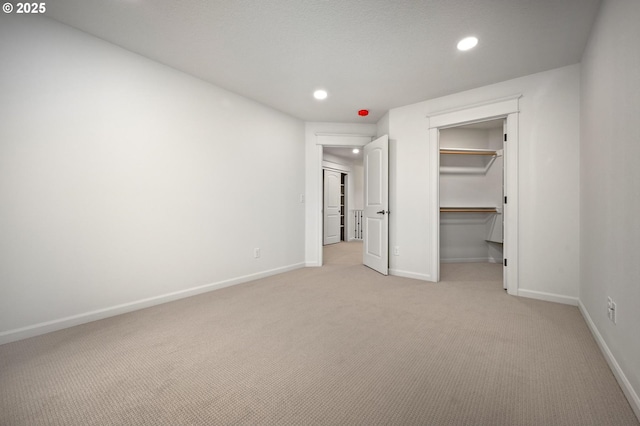 unfurnished bedroom with light carpet, baseboards, recessed lighting, a spacious closet, and a closet