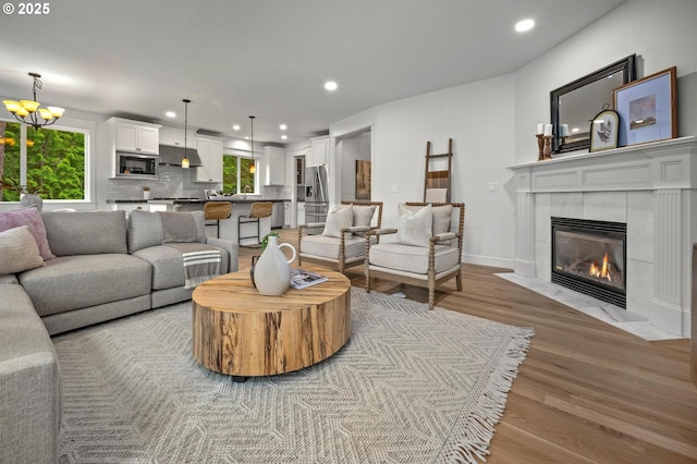 living area with light wood finished floors, a fireplace, recessed lighting, a chandelier, and baseboards