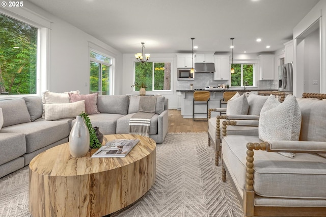 living room featuring healthy amount of natural light, light wood finished floors, a chandelier, and recessed lighting