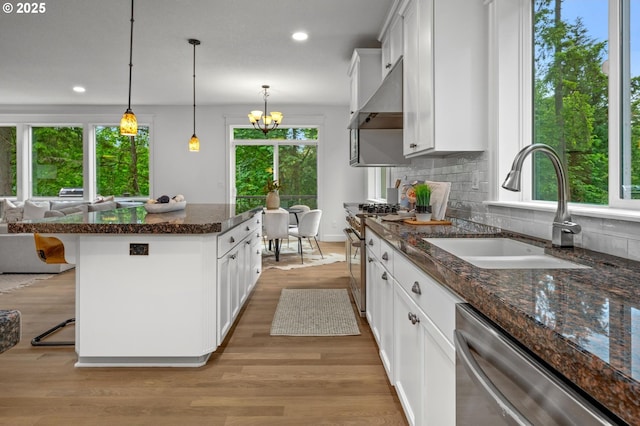 kitchen with appliances with stainless steel finishes, range hood, a sink, a kitchen island, and recessed lighting