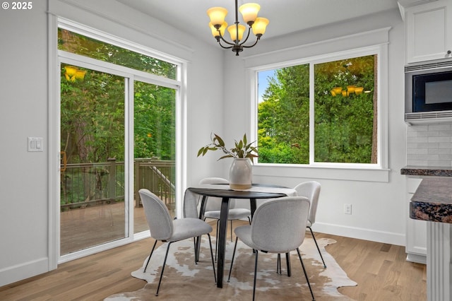 dining room with a chandelier, baseboards, and light wood finished floors