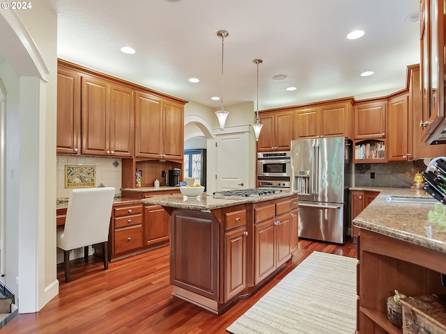 kitchen with pendant lighting, a center island, sink, appliances with stainless steel finishes, and wood-type flooring