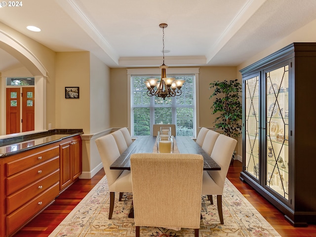 dining space featuring ornamental molding, dark hardwood / wood-style flooring, a raised ceiling, and a notable chandelier