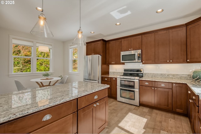 kitchen featuring light stone countertops, recessed lighting, light wood-style flooring, decorative light fixtures, and stainless steel appliances