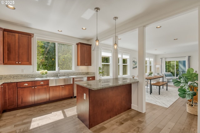 kitchen featuring a sink, dishwasher, a wealth of natural light, and light stone countertops