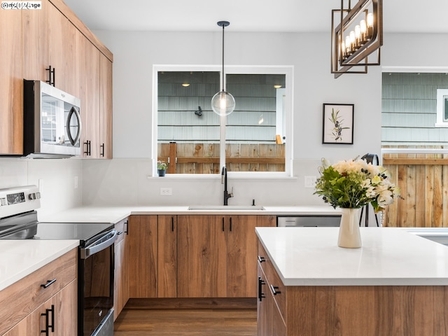 kitchen with pendant lighting, stainless steel appliances, a sink, and light countertops