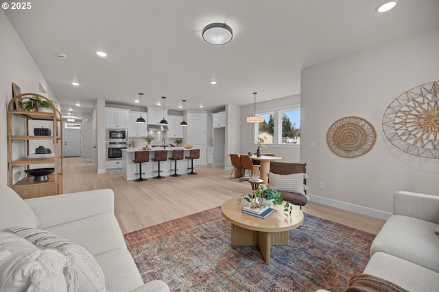 living area featuring recessed lighting, baseboards, and light wood-style flooring