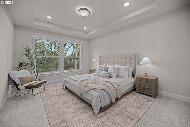 carpeted bedroom with a tray ceiling, recessed lighting, visible vents, and baseboards