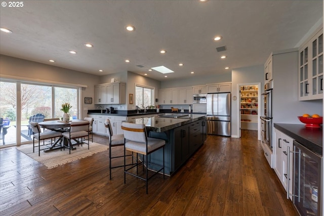 33685 Van Duyn Rd, Eugene, OR 97408 - kitchen featuring wine cooler, appliances with stainless steel finishes, dark countertops, a center island, and recessed lighting