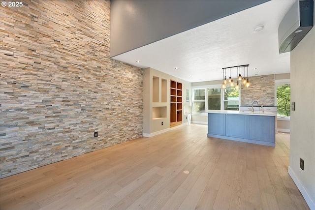 7752 SW Barnes Rd Unit B, Portland, OR 97225 - unfurnished living room with light wood-style floors, a chandelier, a sink, baseboards, and a textured ceiling
