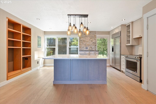 7752 SW Barnes Rd Unit B, Portland, OR 97225 - kitchen featuring stainless steel appliances, light countertops, a sink, light wood-type flooring, and an island with sink
