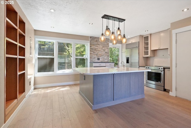 7752 SW Barnes Rd Unit B, Portland, OR 97225 - kitchen with appliances with stainless steel finishes, light wood-type flooring, light countertops, baseboards, and a center island with sink