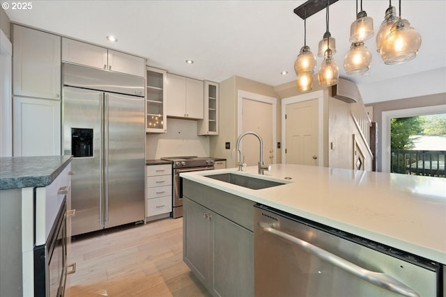 7752 SW Barnes Rd Unit B, Portland, OR 97225 - kitchen with appliances with stainless steel finishes, a sink, light wood-style flooring, recessed lighting, and hanging light fixtures