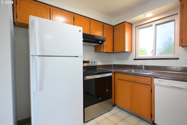 kitchen featuring white appliances, under cabinet range hood, a sink, dark countertops, and brown cabinets