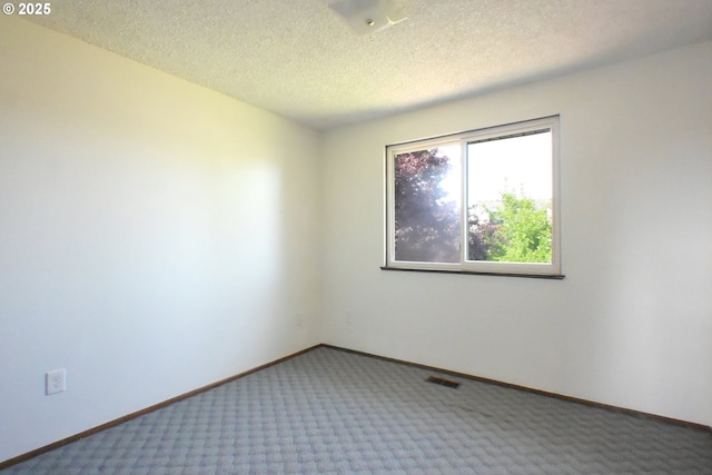 unfurnished room featuring carpet, baseboards, and a textured ceiling