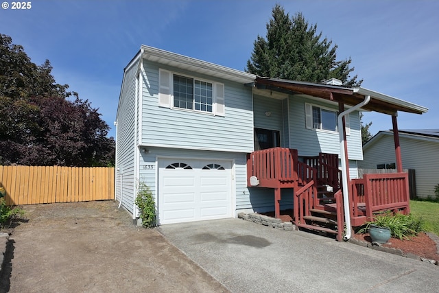 bi-level home featuring concrete driveway, fence, and a garage