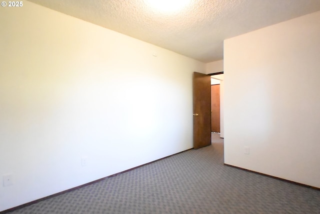carpeted spare room with a textured ceiling and baseboards