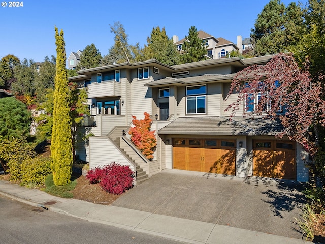 view of front of home featuring an attached garage, stairs, and concrete driveway
