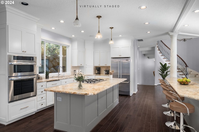 kitchen featuring a kitchen island, white cabinets, ornate columns, stainless steel appliances, and recessed lighting