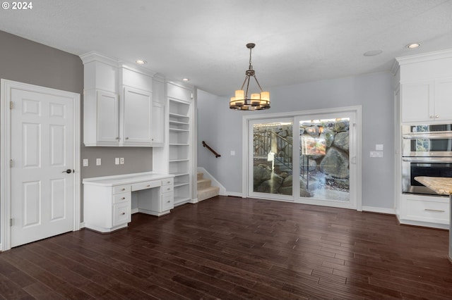 interior space featuring an inviting chandelier, dark wood-style flooring, double oven, built in study area, and white cabinets