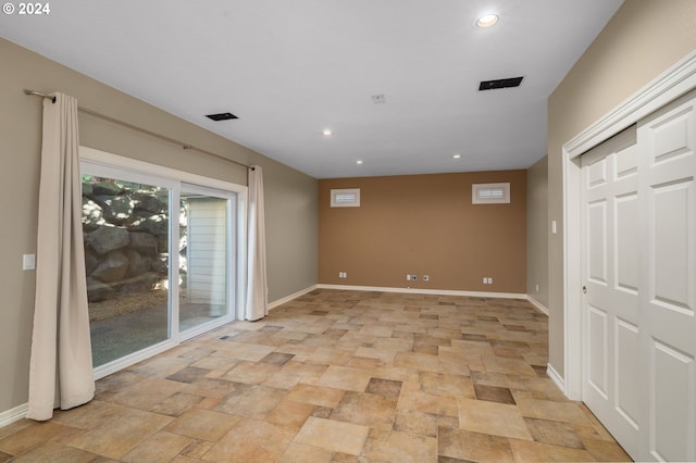 spare room featuring recessed lighting, stone finish flooring, and baseboards