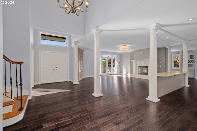 entryway featuring a towering ceiling, a high end fireplace, dark wood finished floors, baseboards, and recessed lighting