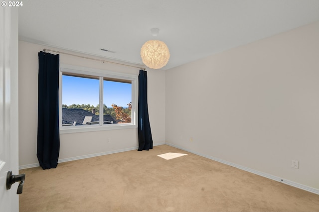 spare room featuring baseboards, visible vents, and light carpet