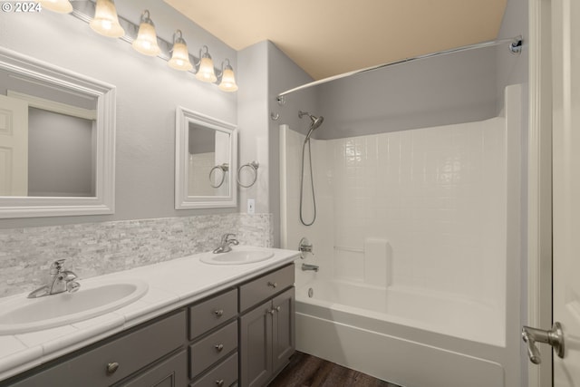 bathroom with double vanity, a sink, shower / bathing tub combination, and tasteful backsplash