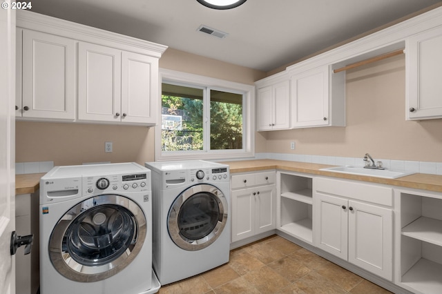 washroom featuring visible vents, a sink, cabinet space, and washing machine and clothes dryer