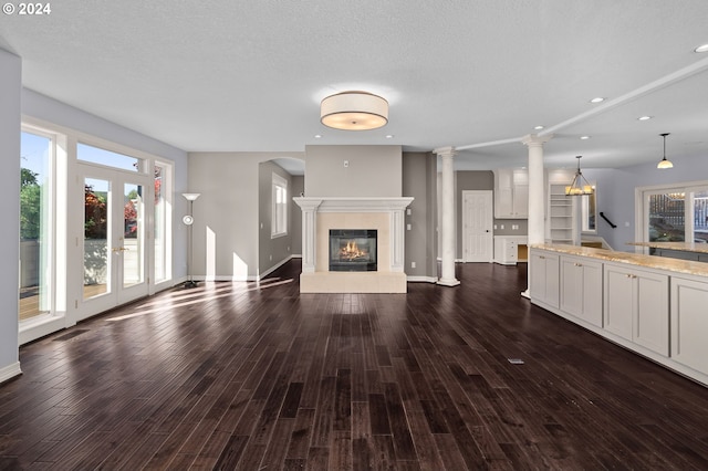 unfurnished living room featuring recessed lighting, plenty of natural light, a tiled fireplace, and dark wood-type flooring