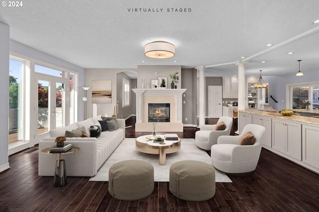 living room featuring decorative columns, dark wood-style flooring, a tiled fireplace, baseboards, and recessed lighting