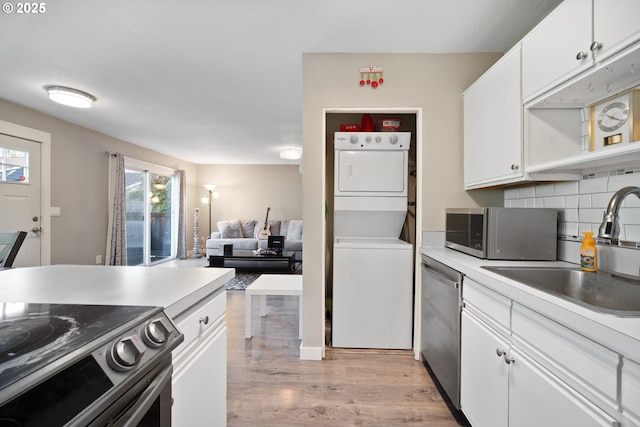 5582 SW Murray Blvd, Beaverton, OR 97005 - kitchen featuring stacked washer and dryer, a sink, stainless steel appliances, light wood-type flooring, and tasteful backsplash