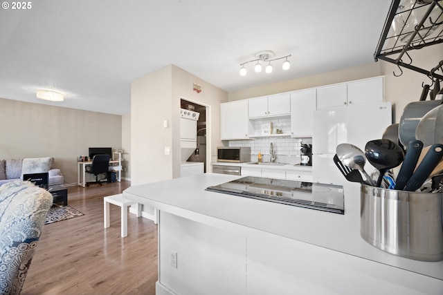 5582 SW Murray Blvd, Beaverton, OR 97005 - kitchen featuring decorative backsplash, light wood finished floors, open floor plan, stacked washer and clothes dryer, and stainless steel appliances