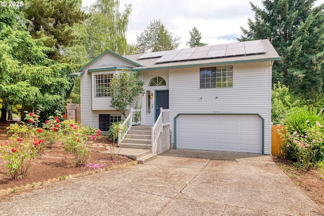 15210 SW 100th Ave, Portland, OR 97224 - raised ranch featuring a garage, solar panels, concrete driveway, and a shingled roof