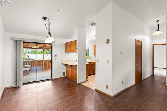 15210 SW 100th Ave, Portland, OR 97224 - kitchen featuring brown cabinetry, light wood-style floors, light countertops, vaulted ceiling, and pendant lighting