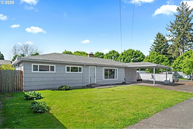 ranch-style home featuring an attached carport, a chimney, fence, aphalt driveway, and a front yard
