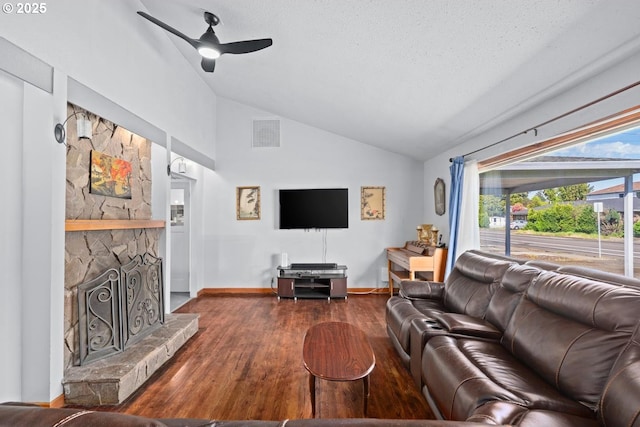 living room with a ceiling fan, baseboards, a stone fireplace, visible vents, and wood finished floors