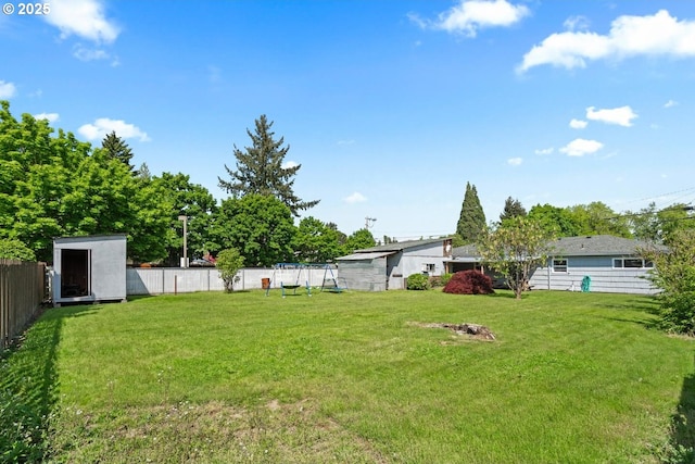 view of yard featuring a storage unit, a fenced backyard, and an outbuilding